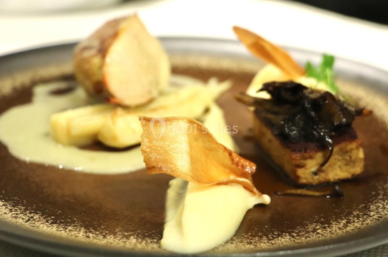 Assiette gastronomique avec viande, purée, légumes racines, champignons et chips croustillantes, présentée avec soin.