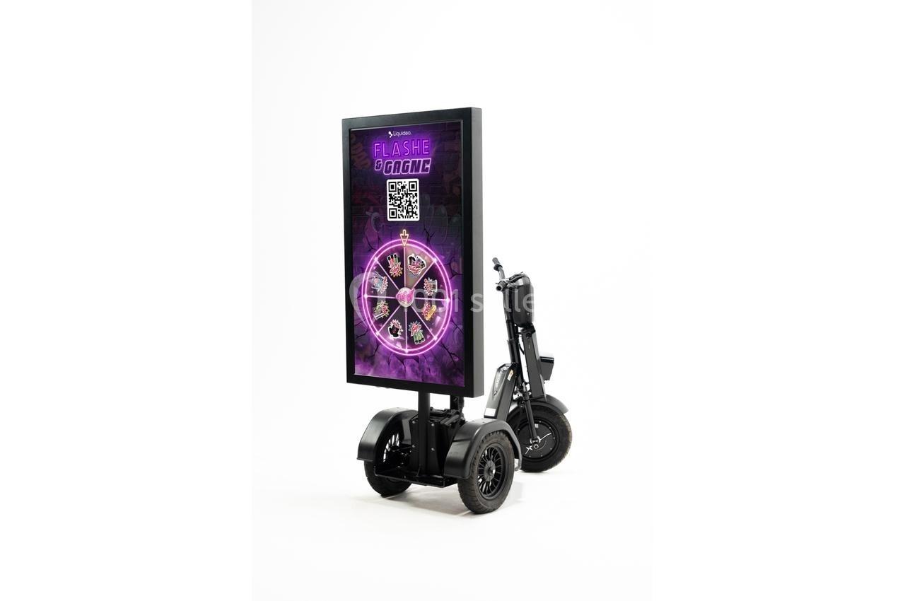 Panneau publicitaire mobile sur un scooter électrique, affichant une roue de jeu violette avec un QR code.