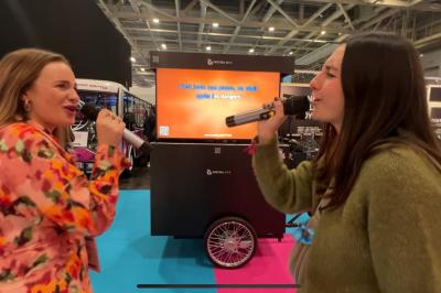 Une DJ joue de la musique sur une scène mobile montée sur un vélo, dans une cour extérieure.