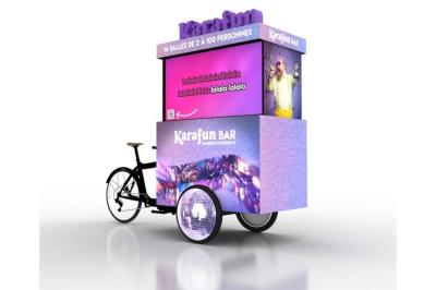 Une DJ joue de la musique sur une scène mobile montée sur un vélo, dans une cour extérieure.