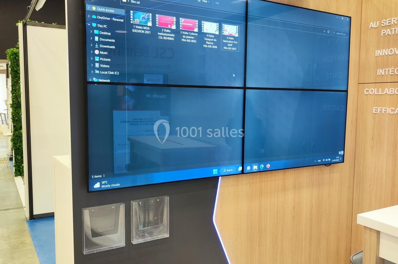Écran mural divisé en quatre sections affichant une interface Windows, installé dans un espace d'exposition moderne.