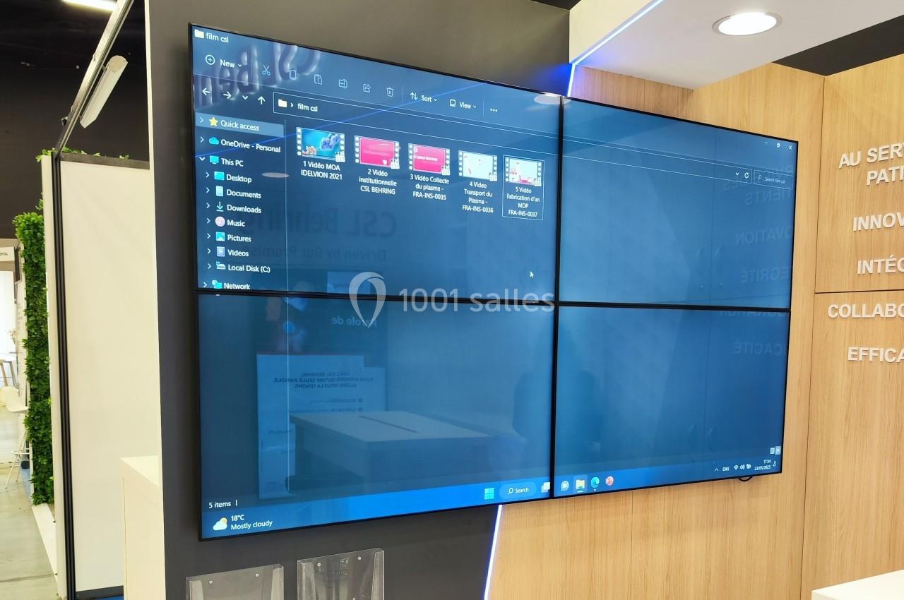 Écran mural affichant une interface Windows avec des dossiers et fichiers, installé dans un espace intérieur moderne.