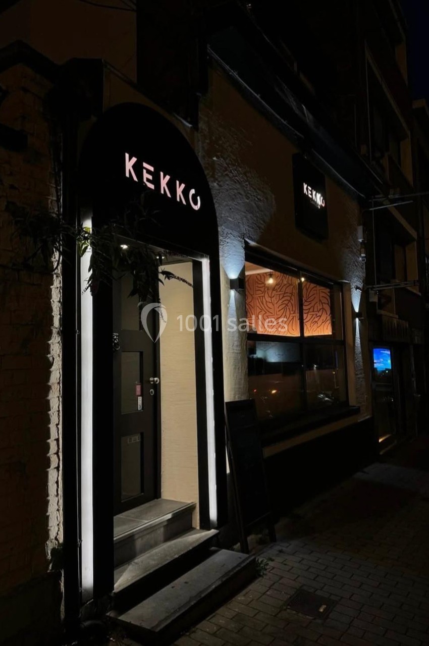 Façade d'un restaurant nommé ’Kekko’ éclairée de nuit, avec une entrée et une vitrine illuminées.