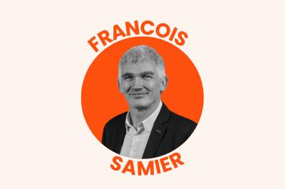 Portrait en noir et blanc d'un homme souriant en costume, sur un fond orange circulaire avec son nom inscrit autour.