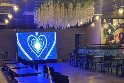 Miniature Location salle Saint-Soupplets (Seine-et-Marne) - The Taj #5 Salle moderne avec écran affichant des cœurs lumineux, tables et chaises noires, plafond décoré de fleurs suspendues.