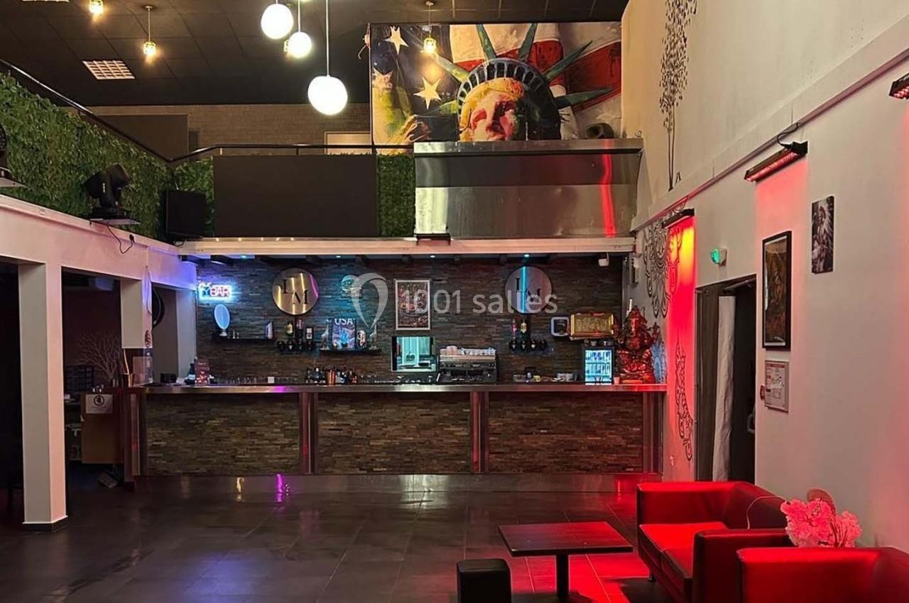 Salle moderne avec bar en pierre, décorations lumineuses, canapés rouges et fresque murale représentant la Statue de la…