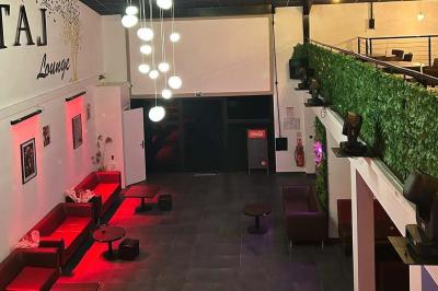 Miniature Location salle Saint-Soupplets (Seine-et-Marne) - The Taj #3 Salle moderne avec écran affichant des cœurs lumineux, tables et chaises noires, plafond décoré de fleurs suspendues.