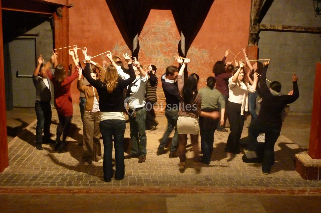 Un groupe de personnes dans une salle, levant les bras et tenant des cadres en bois dans un cadre artistique ou participatif.