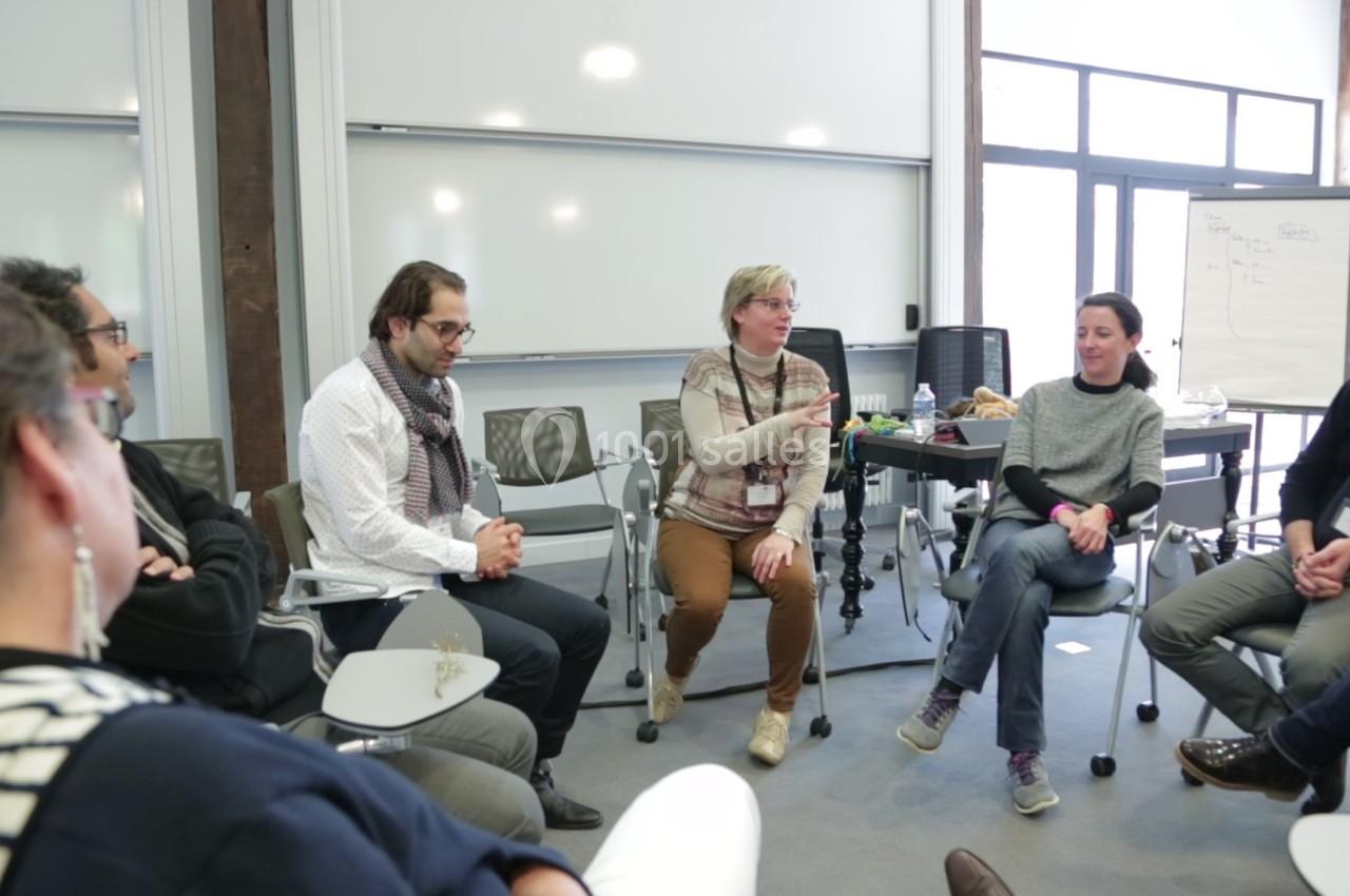 Un groupe de personnes assises en cercle dans une salle de réunion, discutant activement.