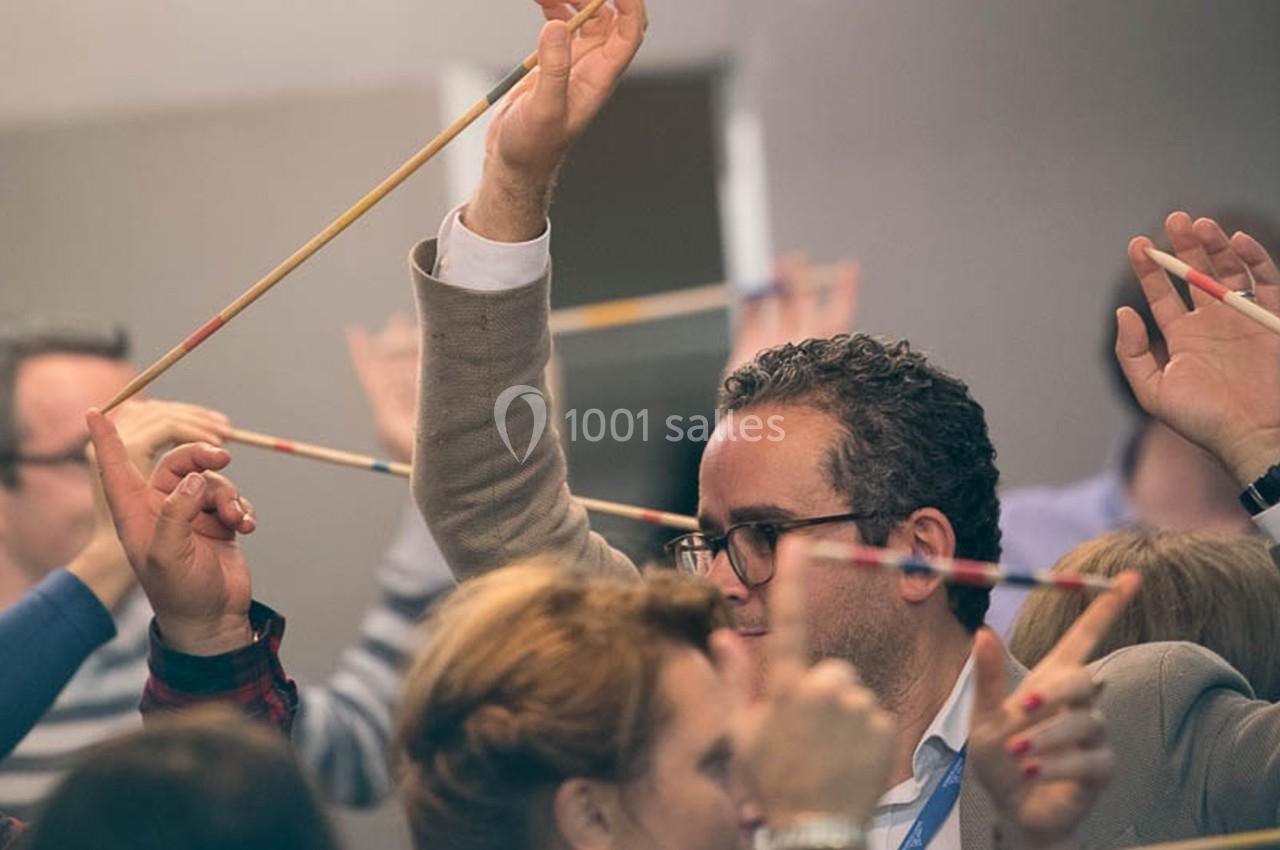Des personnes participent à une activité collaborative en groupe, utilisant des baguettes pour un exercice collectif.