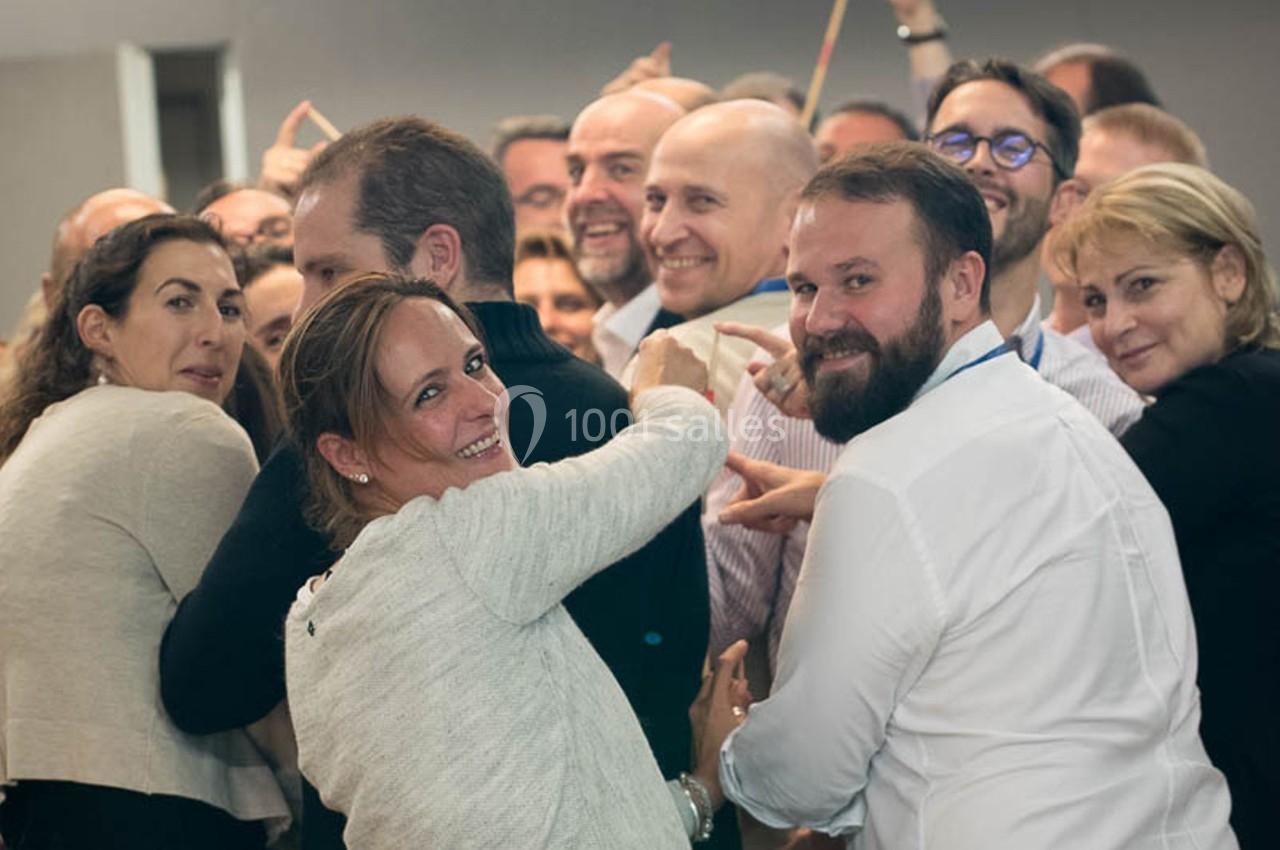 Un groupe de personnes souriantes rassemblées dans une ambiance conviviale lors d'un événement en intérieur.