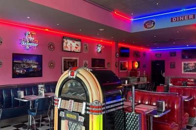 Miniature Location salle Mareuil-lès-Meaux (Seine-et-Marne) - Texas #2 Intérieur d'un diner rétro avec banquettes rouges, sol en damier noir et blanc, et décoration vintage.