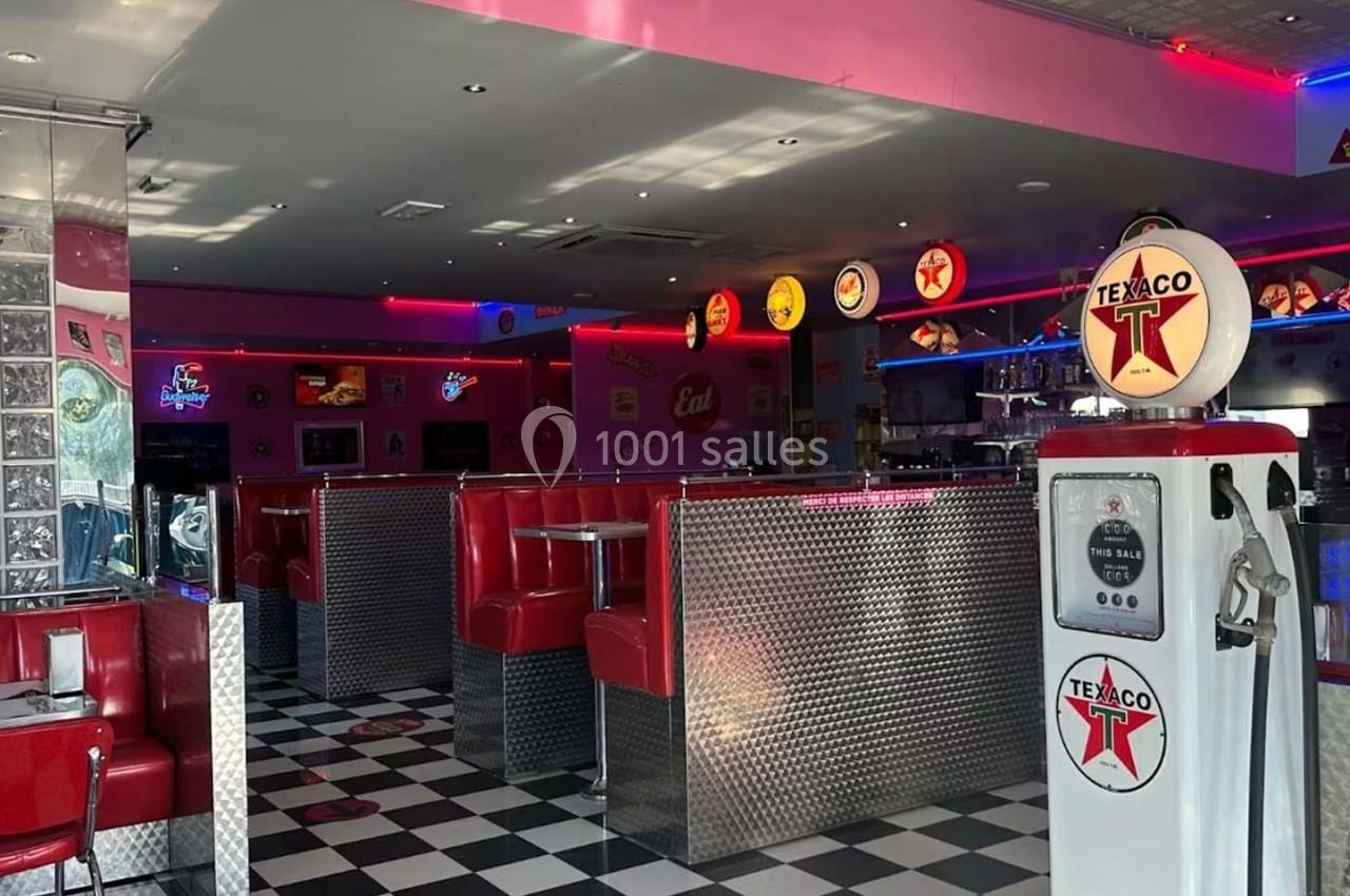 Intérieur d'un diner rétro avec banquettes rouges, sol en damier noir et blanc, et décoration vintage.