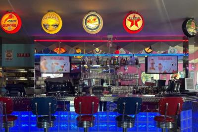 Miniature Location salle Mareuil-lès-Meaux (Seine-et-Marne) - Texas #3 Intérieur d'un diner rétro avec banquettes rouges, sol en damier noir et blanc, et décoration vintage.