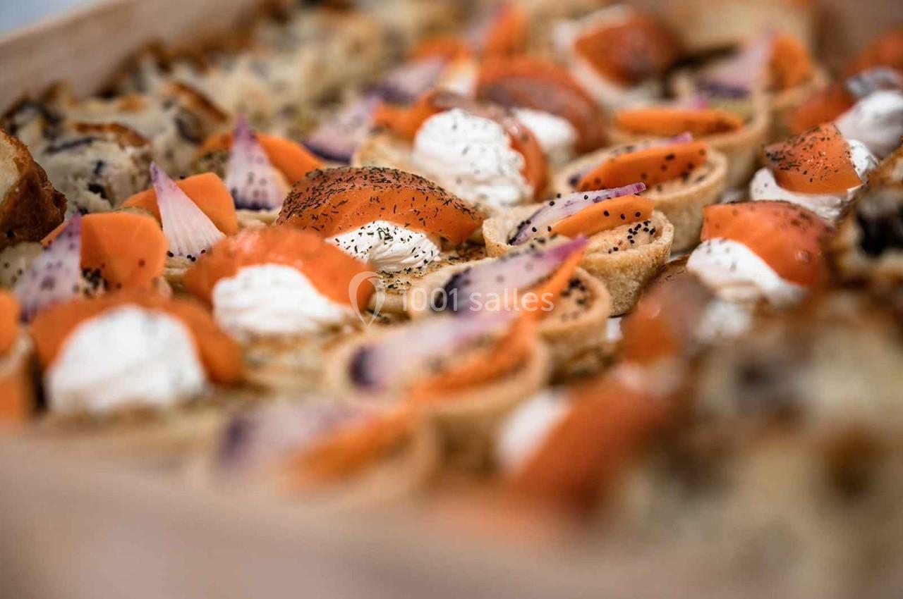 Plateau de canapés garnis de saumon fumé, fromage frais et herbes, disposés sur une table.