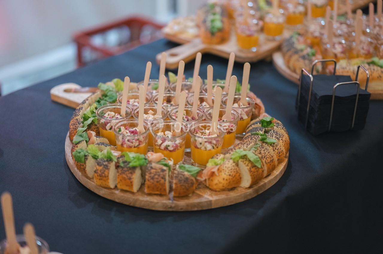 Plateaux de verrines colorées et pains garnis disposés sur une table noire pour un buffet.