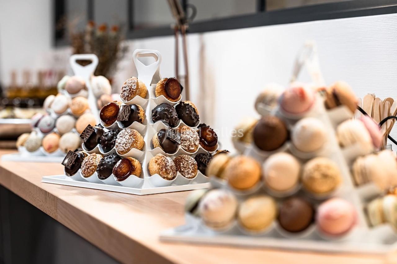 Présentoirs en forme de pyramide garnis de macarons et de petits choux, disposés sur un comptoir en bois.