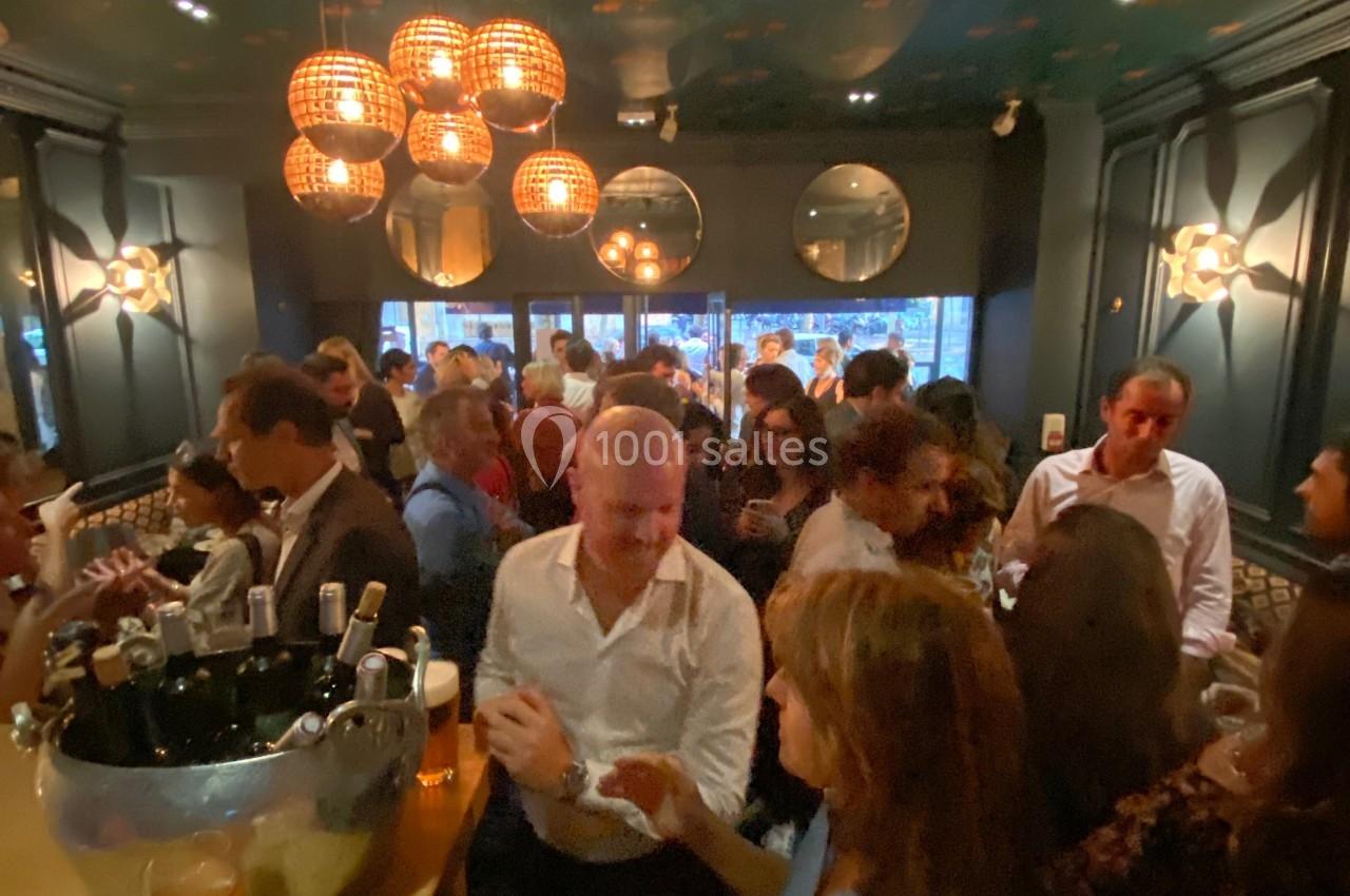 Groupe de personnes discutant dans un bar animé avec une lumière tamisée et une décoration élégante.