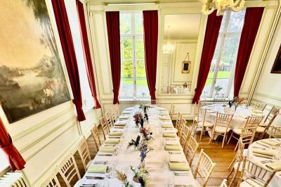 Miniature Location salle Namur (Namur) - Château de Beez #5 Groupe de personnes assises en extérieur lors d'une cérémonie, entourées d'arbres et de fleurs sous un ciel partiellement…