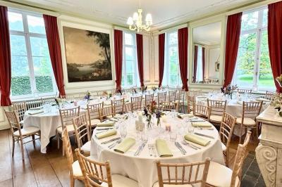Miniature Location salle Namur (Namur) - Château de Beez #6 Groupe de personnes assises en extérieur lors d'une cérémonie, entourées d'arbres et de fleurs sous un ciel partiellement…
