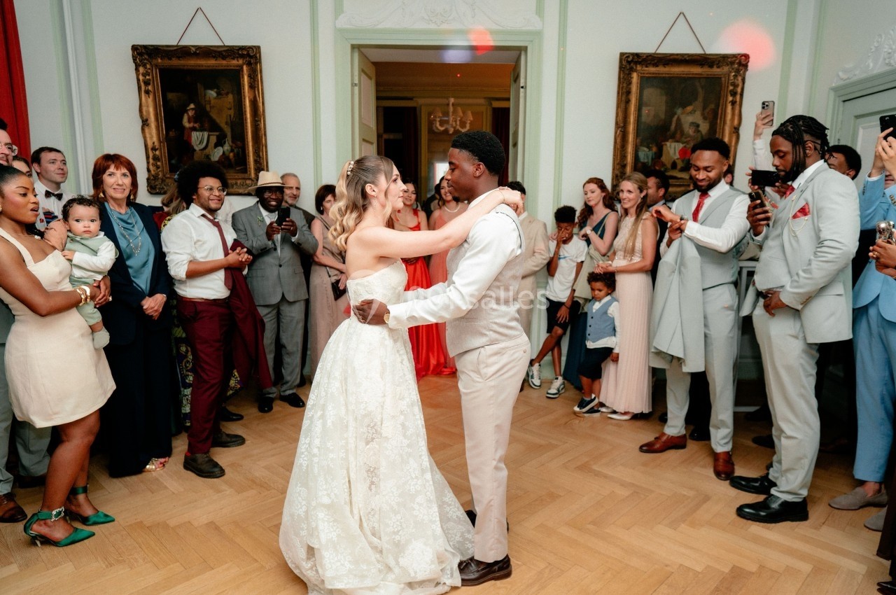Un couple danse lors d'une réception de mariage, entouré d'invités qui les regardent et prennent des photos.