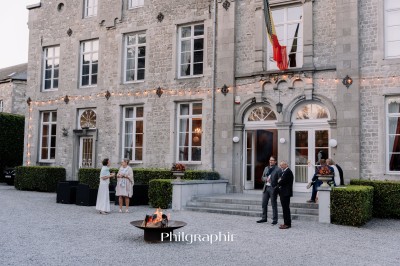 Miniature Location salle Namur (Province de Namur) - Château de Beez #36 Groupe de personnes rassemblées sous une tente beige sur une terrasse en bois, dans un jardin arboré.
