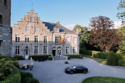 Miniature Location salle Namur (Province de Namur) - Château de Beez #38 Groupe de personnes rassemblées sous une tente beige sur une terrasse en bois, dans un jardin arboré.