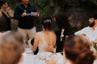 Un couple souriant marche main dans la main au milieu d'invités applaudissant lors d'une cérémonie en plein air.