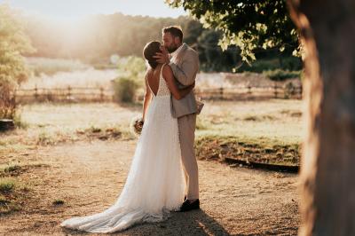 Un couple souriant marche main dans la main au milieu d'invités applaudissant lors d'une cérémonie en plein air.