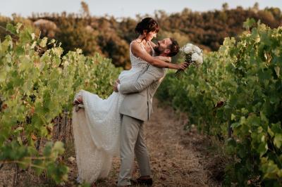 Un couple souriant marche main dans la main au milieu d'invités applaudissant lors d'une cérémonie en plein air.