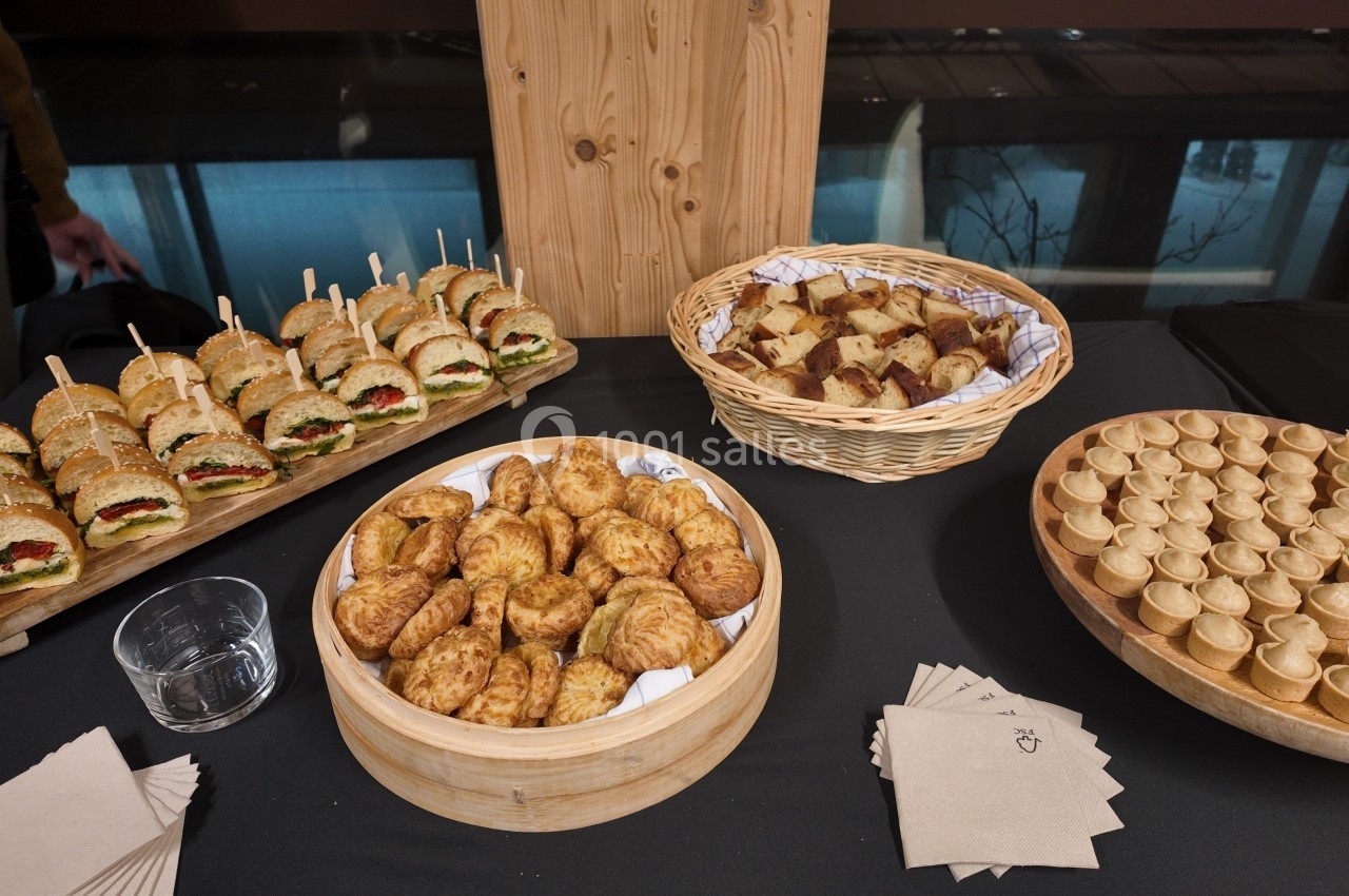 Plateau de buffet avec mini-sandwichs, feuilletés, bouchées salées et morceaux de pain dans des paniers et assiettes.
