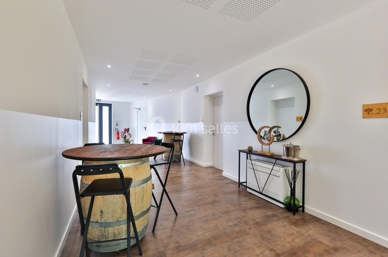 Couloir lumineux avec table haute en tonneau, miroir rond, console décorative et porte numérotée.