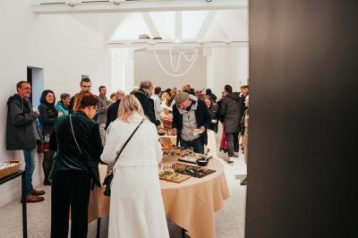 Des personnes discutent debout dans un espace extérieur, entourées de verdure et de mobilier de jardin.