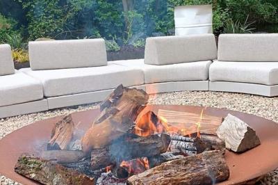 Des personnes discutent debout dans un espace extérieur, entourées de verdure et de mobilier de jardin.