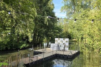 Des personnes discutent debout dans un espace extérieur, entourées de verdure et de mobilier de jardin.