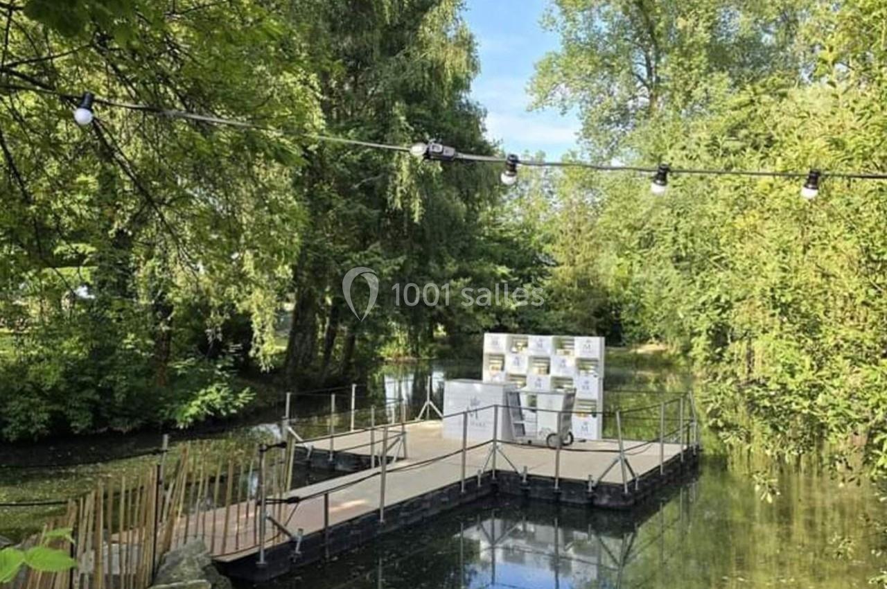 Plateforme flottante sur un étang entouré de végétation, équipée de ruches et éclairée par des guirlandes lumineuses.