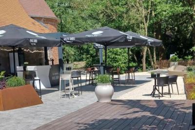 Des personnes discutent debout dans un espace extérieur, entourées de verdure et de mobilier de jardin.