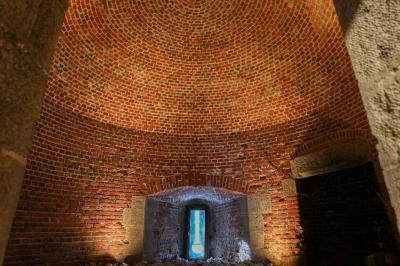 Des personnes discutent debout dans un espace extérieur, entourées de verdure et de mobilier de jardin.