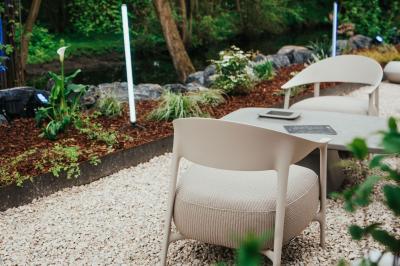 Des personnes discutent debout dans un espace extérieur, entourées de verdure et de mobilier de jardin.