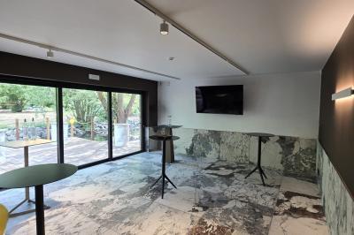 Des personnes discutent debout dans un espace extérieur, entourées de verdure et de mobilier de jardin.