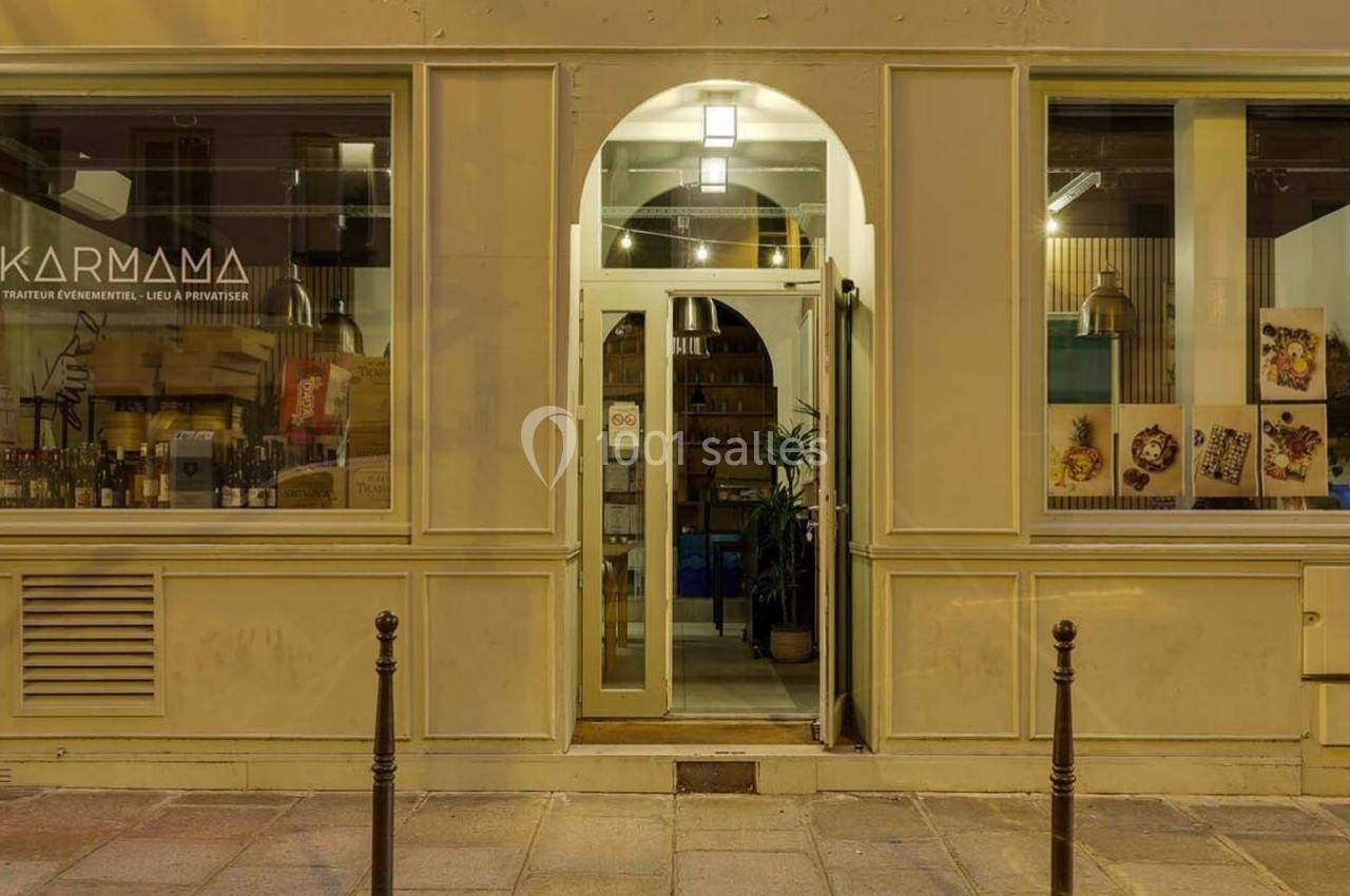 Façade d'un restaurant avec une vitrine éclairée, une porte centrale et des affiches de plats sur la droite.