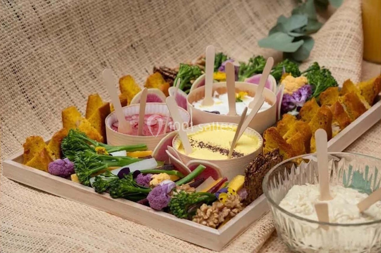Plateau de légumes colorés, dips variés et toasts dorés disposés sur une nappe en toile beige.