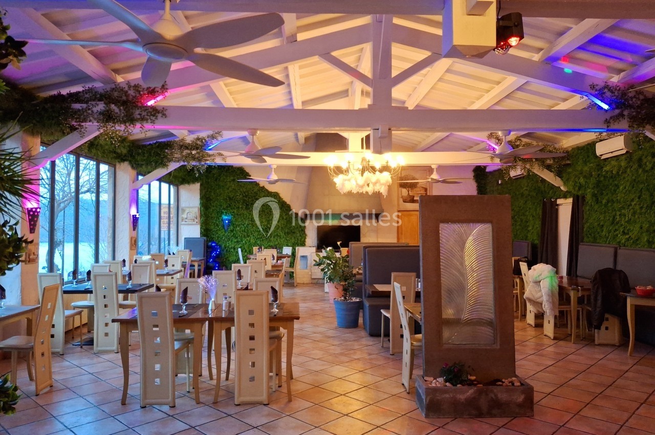 Salle de restaurant lumineuse avec plafond en poutres apparentes, murs végétalisés et tables en bois clair.