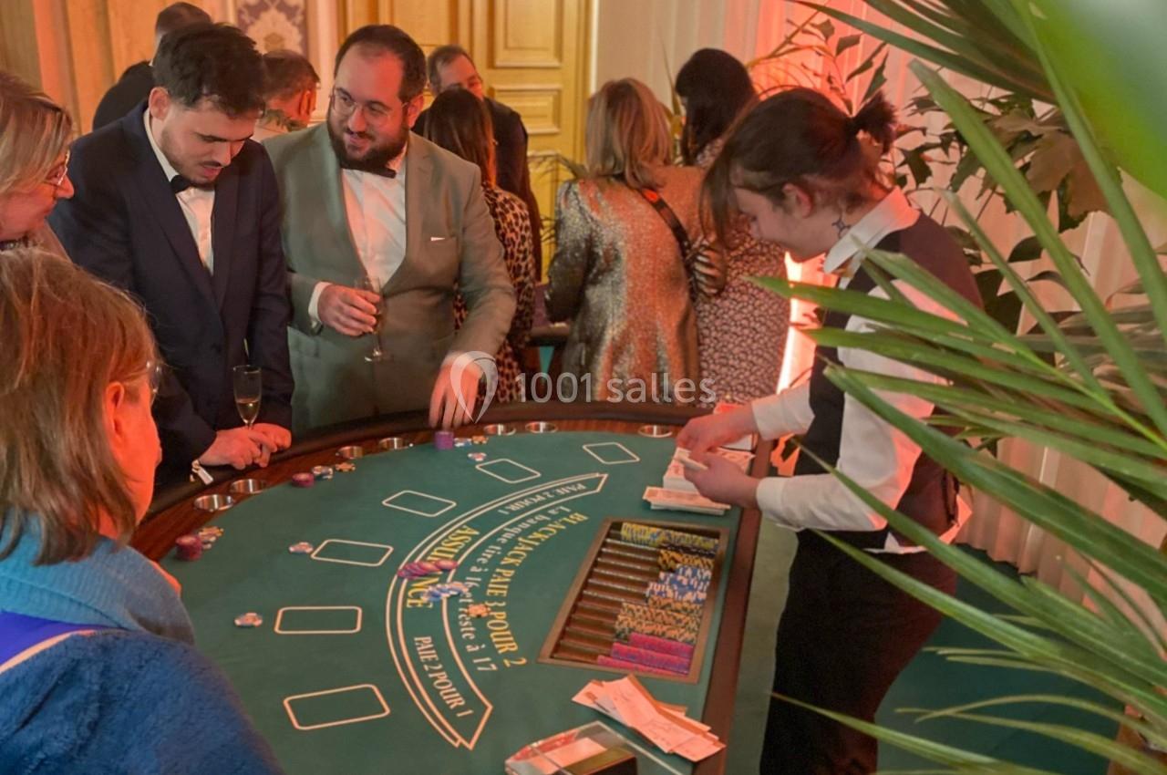 Des personnes jouent au blackjack autour d'une table de casino, avec un croupier distribuant les cartes.