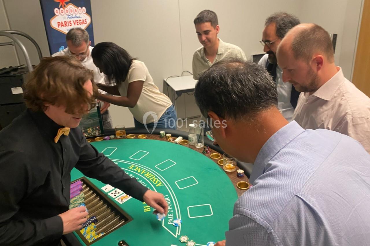Des personnes jouent autour d'une table de casino avec un croupier distribuant des jetons.