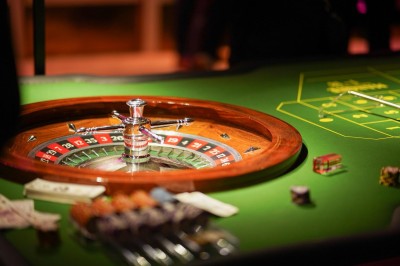 Une femme tourne une roue colorée de jeu avec des chiffres dans un environnement éclairé en rose.
