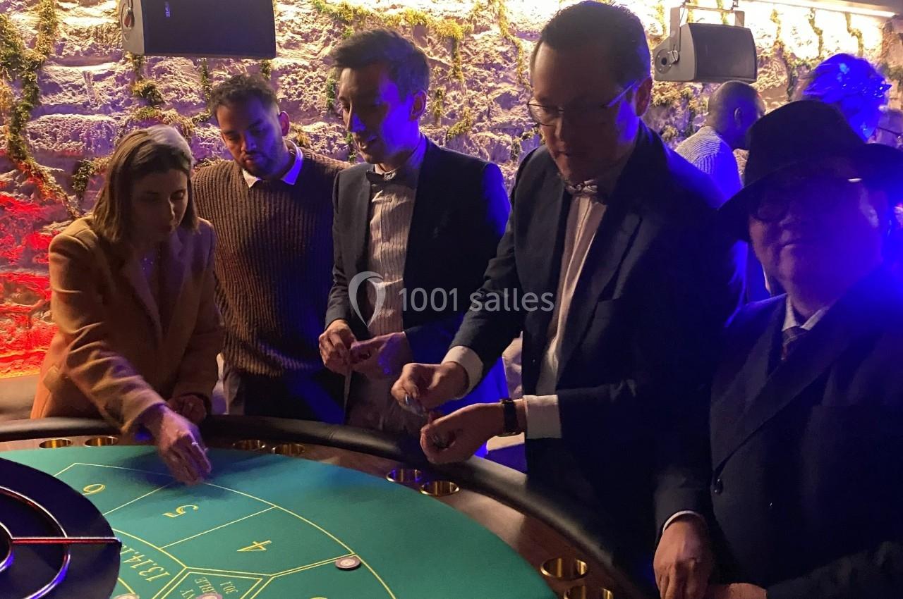 Des personnes jouent à une table de roulette dans un casino, dans une ambiance tamisée et conviviale.