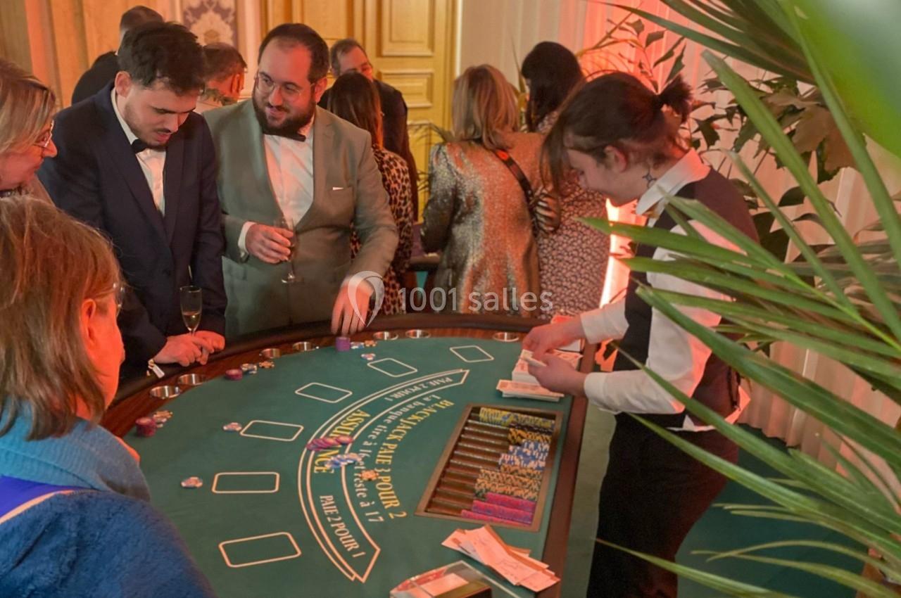 Des personnes jouent au blackjack autour d'une table de casino, avec un croupier distribuant les cartes.