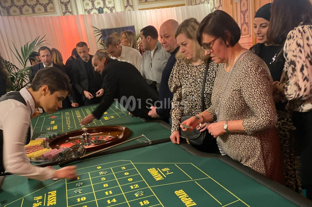 Des personnes jouent à la roulette dans un casino, observant attentivement la table et les mises.