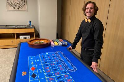 Miniature L'As du Casino #6 Table de jeu de casino avec tapis vert numéroté et porte-gobelets intégrés, entourée de personnes debout.
